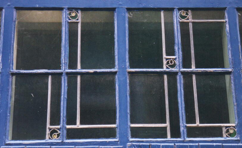 Maurice Liétartstraat 56-58, glas-in-lood in T-vormig <a href='/nl/glossary/257' class='info'>venster<span>Licht- en/of luchtopening in een muur.</span></a> op benedenverdieping (foto 2002).