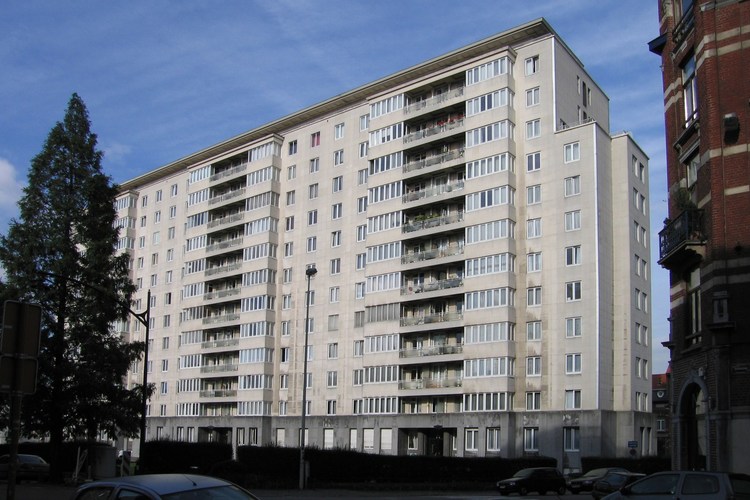 Occupant le deuxième tronçon de la rue du Noyer, vaste barre de logements conçue en 1954 par les architectes Alexis Dumont et Paul Goolaerts en remplacement du dépôt de corbillards désaffecté (photo 2006).