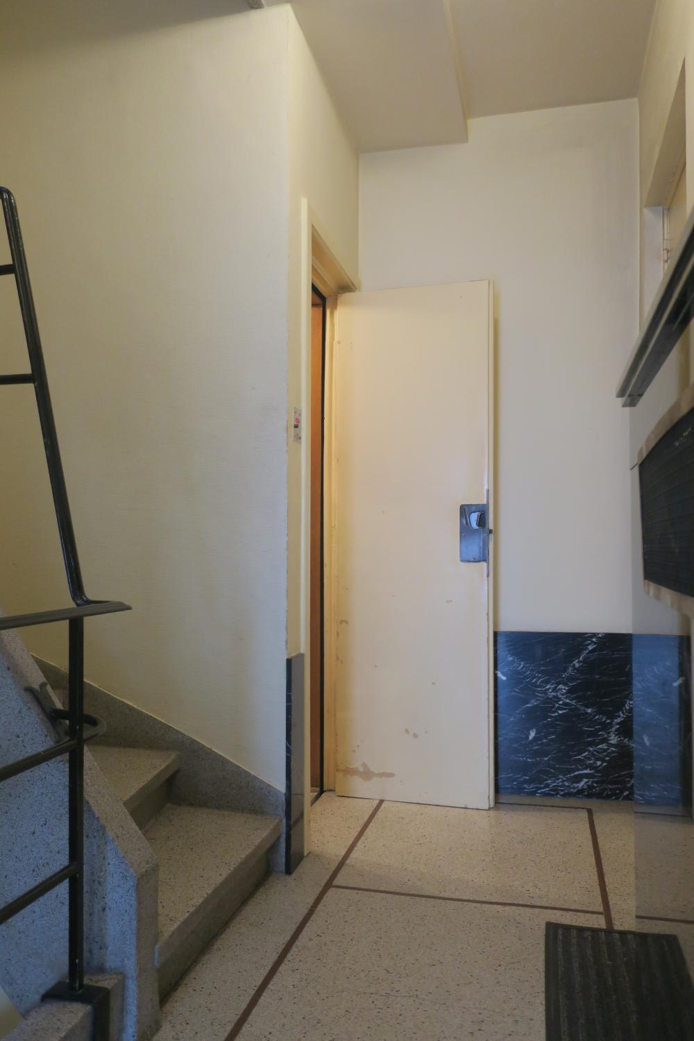 Rue Jean-Baptiste Colyns 46. Ascenseur au rez-de-chaussée avec porte palière ouverte © Homegrade, 2023